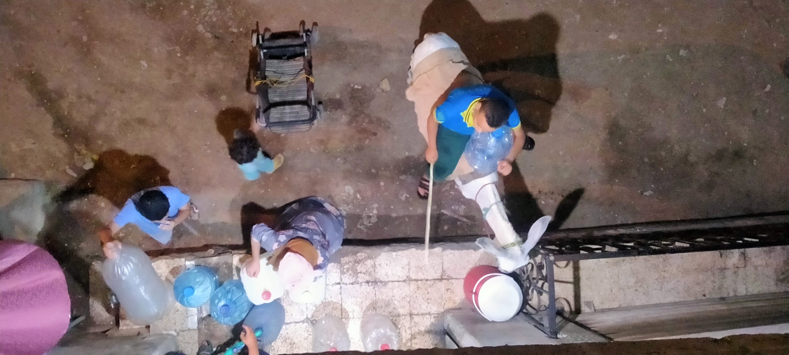 في الليل الأطفال والنساء يشترون المياه من محطة مياه خاصة